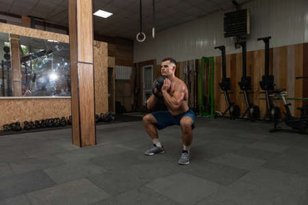 Muscular powerful man exercising with heavy kettlebell in cross fit gym. Functional training with...