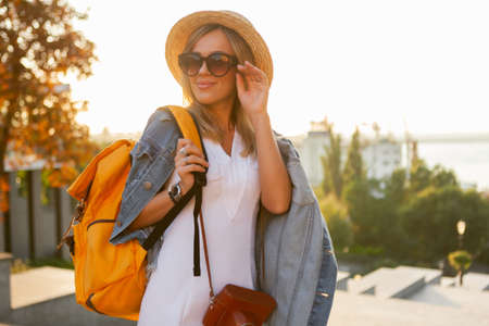Portrait of young smiling woman tourist with a big backpack in the city at sunrise. travel conceptの写真素材