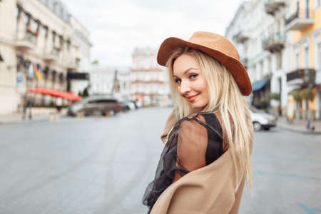 Portrait of young stylish blonde woman in autumn coat and felt hat in a European city. beautiful attractive girlの写真素材