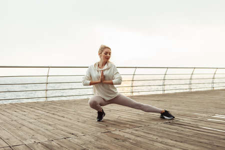 Young slim fit woman practicing yoga asana pose on the beach. fitness girl. Namasteの写真素材