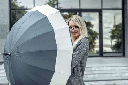Happy business woman open umbrella on the background of a business office. waiting for the rainの写真素材