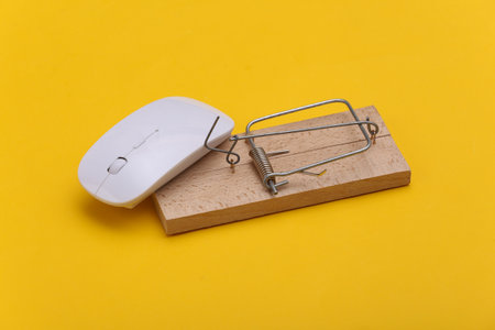 Mousetrap with pc mouse on a yellow background. Online trapの写真素材