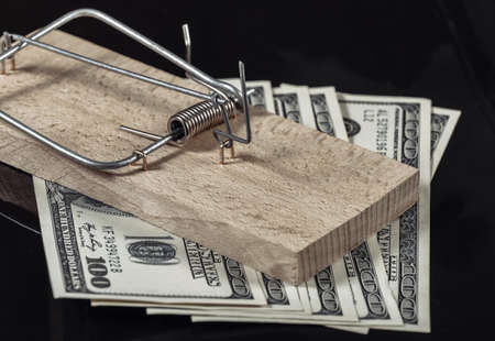Mousetrap with one hundred dollar bills isolated on black background. Cheating, business concept, loans or creditの写真素材