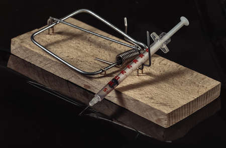 Mousetrap with house figurine isolated on black background. Cheating when buying or renting homeの写真素材