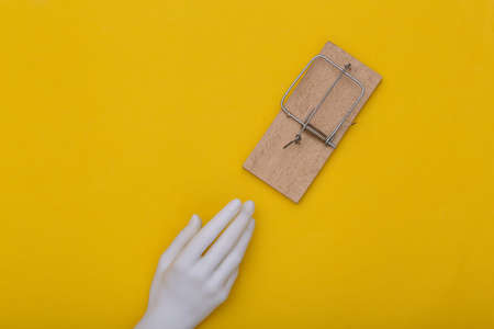 The mannequin's hand reaches for a mousetrap on yellow background. Trap concept. top viewの写真素材