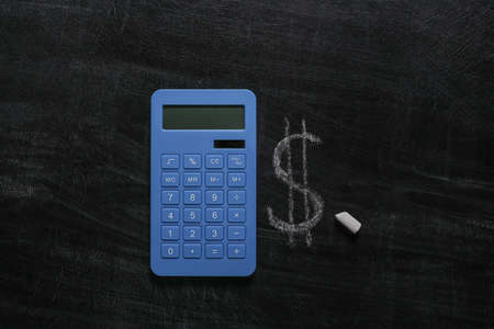 Dollar symbol $ chalk hand drawn on blackboard and calculatorの写真素材