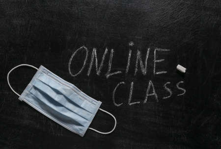 Online class text chalk hand drawn on blackboard and medical mask.の写真素材