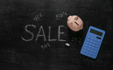 piggy bank and calculator, Sale word chalk hand drawn on blackboardの写真素材