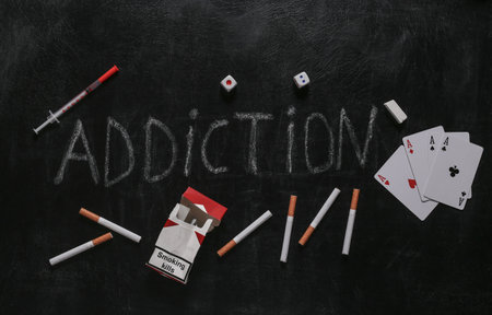 Gambling, nicotine and drug addiction. Word addiction chalk hand drawn on blackboard.の写真素材