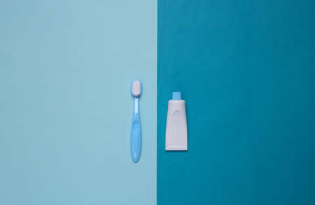 Toy toothbrush and a tube of toothpaste on a blue background. top view. minimalismの写真素材