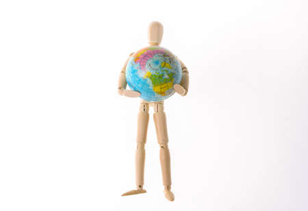 Wooden puppet holding globe isolated on white backgroundの写真素材