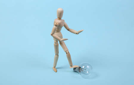 Wooden puppet and light bulb on a blue background.の写真素材