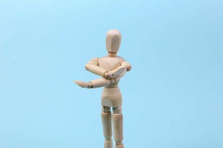 Wooden puppet stretches arms isolated on blue background. Healthy lifestyle, sport conceptの写真素材