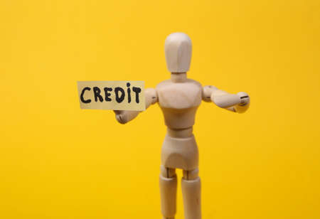 Text credit with wooden puppet figure on yellow backgroundの写真素材