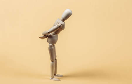 Sad or frustrated wooden puppet on yellow background