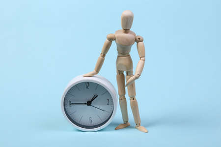 Wooden puppet and clock on a blue background.の写真素材