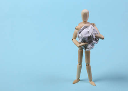 Wooden puppet holding crumpled ball of paper on blue backgroundの写真素材