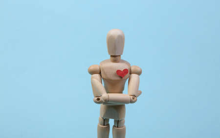 Wooden puppet with a heart on a blue background.の写真素材