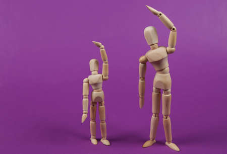 Two wooden puppets are doing aerobics exercise on a purple background. healthy lifestyle concept