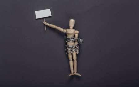 Protesting activist wooden puppet wrapped in a steel with blank banner on gray background. meeting....