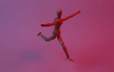 Happy wooden puppet mannequin in red blue neon light.