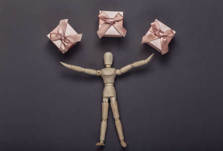 Wooden puppet mannequin and gift boxes on gray background