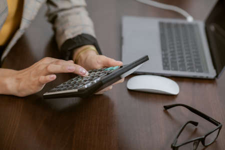 Close-up of hands, woman counts on calculator in office