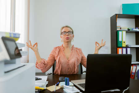 Business woman meditates at the workplace at the table in office.の写真素材