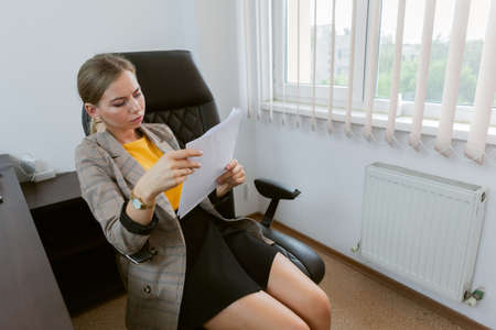 Business lady carefully examines documents in her officeの写真素材