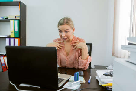 Business woman communicates by video call while looking into a laptop while sitting at a table in her office. Online conference, video callの写真素材