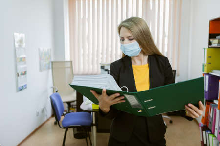 business woman in medical mask holding folder in office