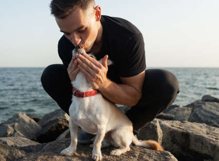 Cute dog with owner man spend time together on the coastの写真素材
