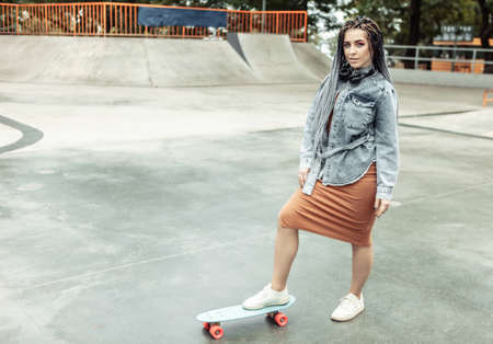 Extraordinary female millennial skater with colorful makeup, African braids in a skate park. Youth, lifestyle conceptの写真素材