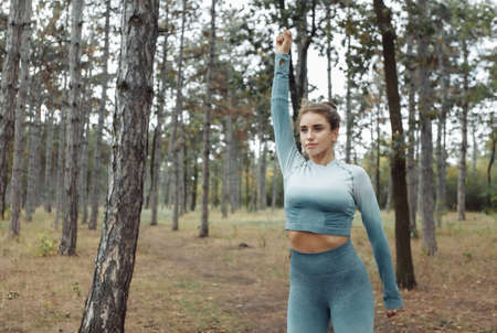 Attractive fitness woman with perfect body doing warm-up or stretching exercise in the forest. healthy lifestyleの写真素材