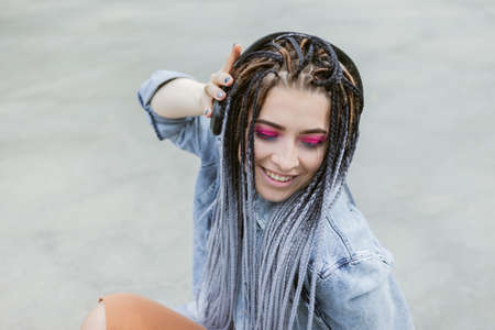 Cheerful Extraordinary Millennial Woman with Bright Makeup and African Braidsの写真素材