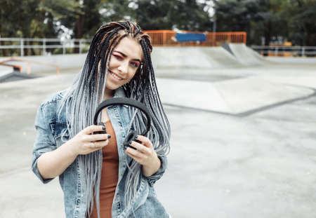 Extraordinary millennial woman with colorful makeup, African braids listening to music on headphones. Youth, lifestyle conceptの写真素材