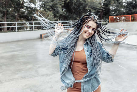 Extraordinary millennial woman with colorful makeup, African braids listening to music on headphones. Youth, lifestyle conceptの写真素材