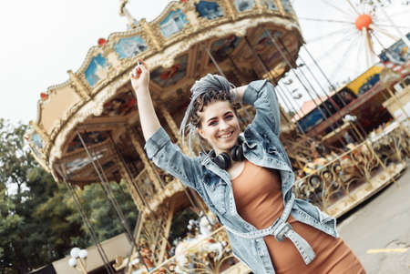 Extraordinary emotional cheerful woman with African braids and bright makeup spends time in amusement park. lifestyleの写真素材