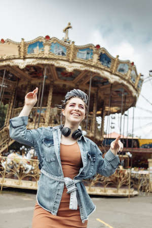Extraordinary emotional cheerful woman with African braids and bright makeup spends time in amusement park. lifestyleの写真素材