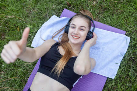 Portrait of a cheerful fit woman lying on a mat in the park. healthy lifestyleの写真素材