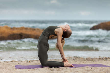 Pretty young healthy yogi woman practicing hatha yoga or asana posture at sea coast with stones. healthy lifestyle.の写真素材