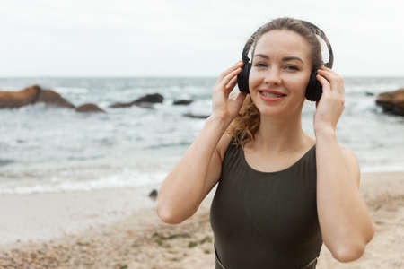 Attractive caucasian fit woman listening to music with headphones on the beachの写真素材