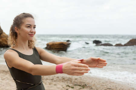 Fit woman works out with fitness rubber bands on the beach.