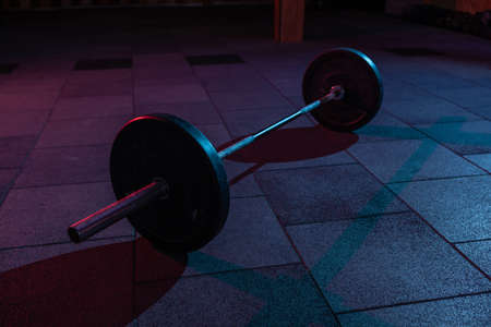 Barbell in a dark grungy gym with blue red neon lightの写真素材