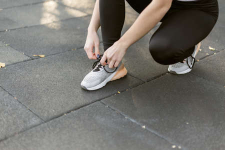 Crop photo fit woman tying the laces of a sneaker close-up and getting ready for a workoutの写真素材