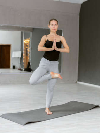 Slim yogi attractive woman practicing yoga hatha. Doing indoor yoga on the mat. Vrksasana,Tree pose....