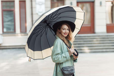 Attractive woman in autumn clothes with umbrella in the city.の写真素材