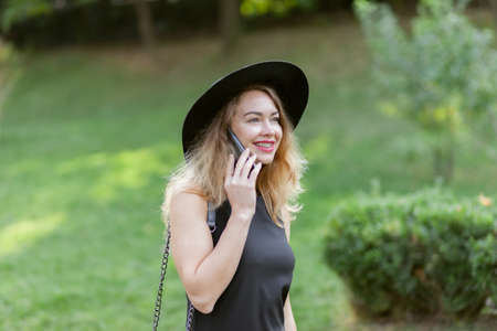 Portrait of a beautiful woman with braces wearing in hat talking on the phone outdoors