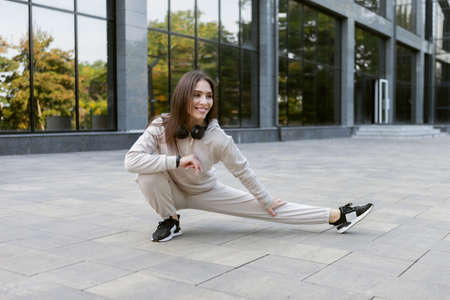 Fit brunette runner woman working out outdoors. Feminine sportswoman in sportswear practices stretching or warming up her arms before training. healthy lifestyleの写真素材
