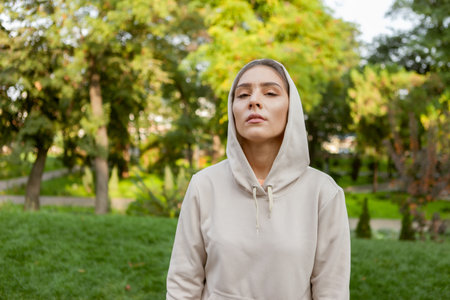 Portrait of a stylish fitness woman in a hood in a park outdoors. fitness conceptの写真素材